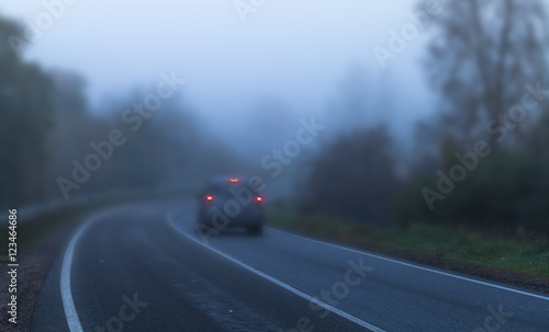Car with red stoplights on foggy highway