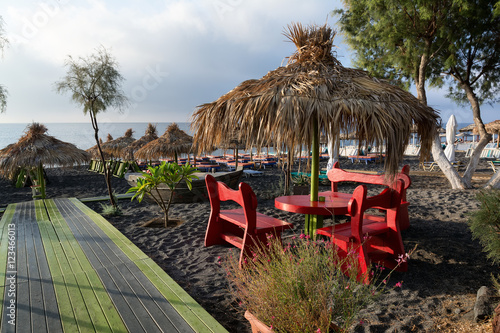 Straw umbrellas and tanning beds on Perissa beach, Santorini, Greece photo