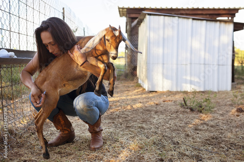 Female farmer injecting goat on field photo