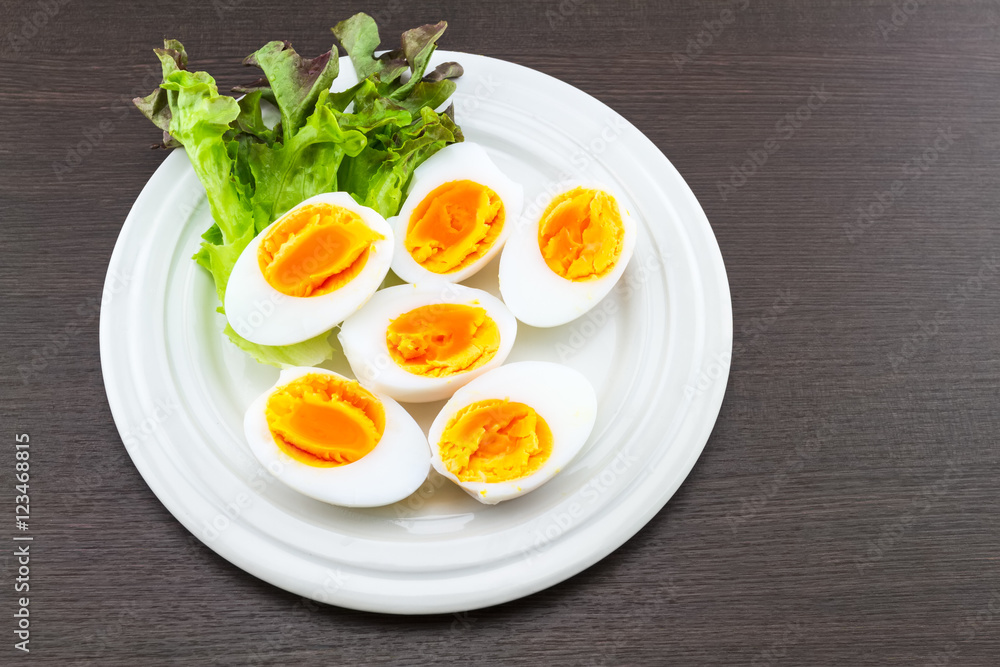 Close up medium soft boiled duck egg portion and green salad in dish Close up medium soft boiled duck egg portion and green salad in dish
