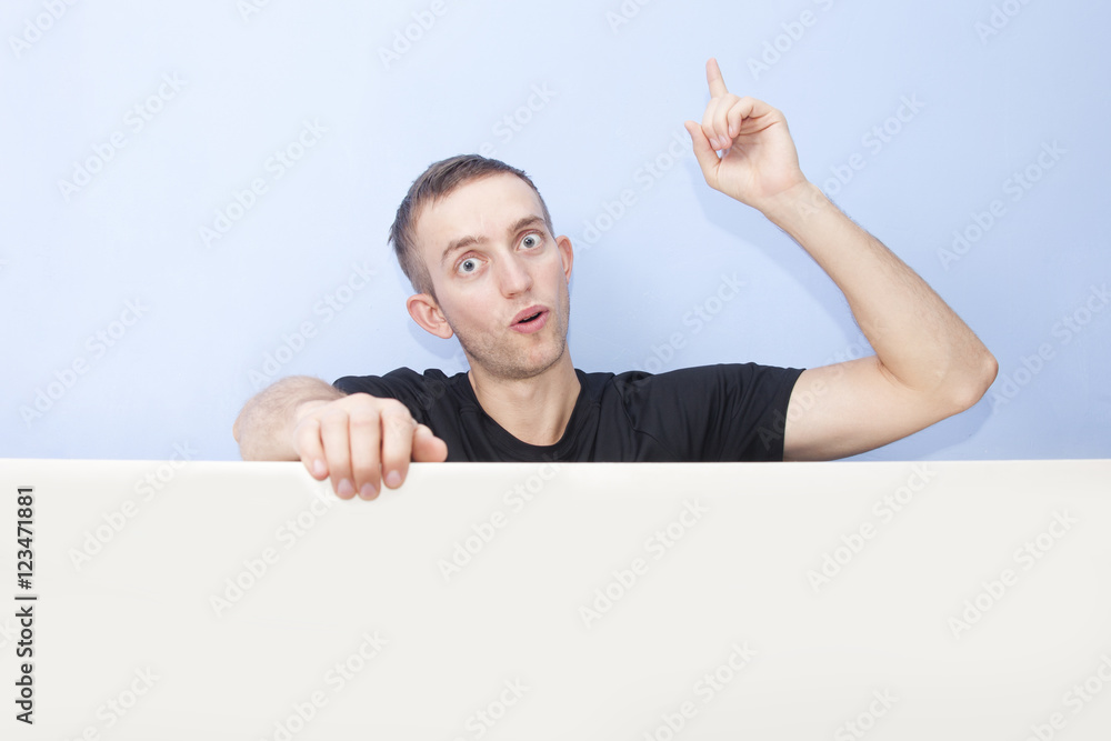 Surprised young man portrait. Finger pointing up. Advertising te Surprised young man portrait. Finger pointing up. Advertising te