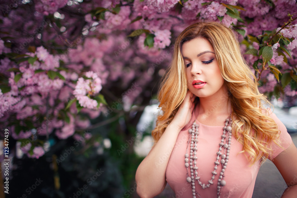 Young beautiful blonde girl with long hair in a pink dress near the cherry trees Young beautiful blonde girl with long hair in a pink dress near the cherry trees