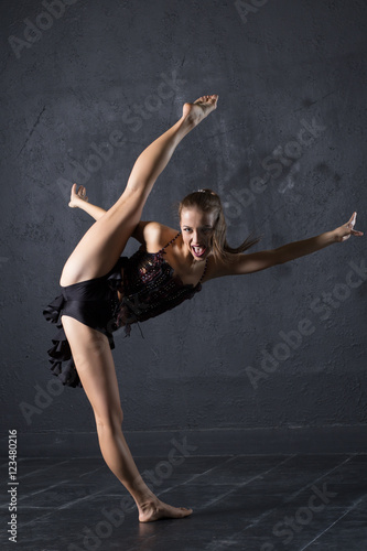 Young professional dancer make a twine against textured wall background