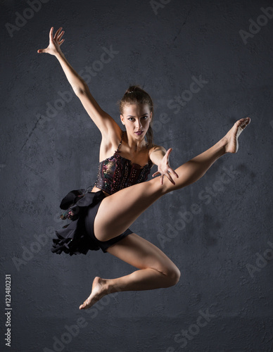 Young professional dancer jumping against textured wall background