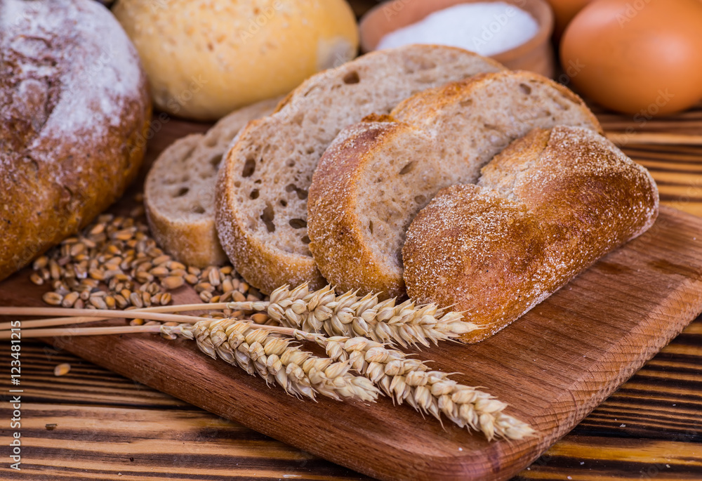 Assortment of baked bread on wooden table background