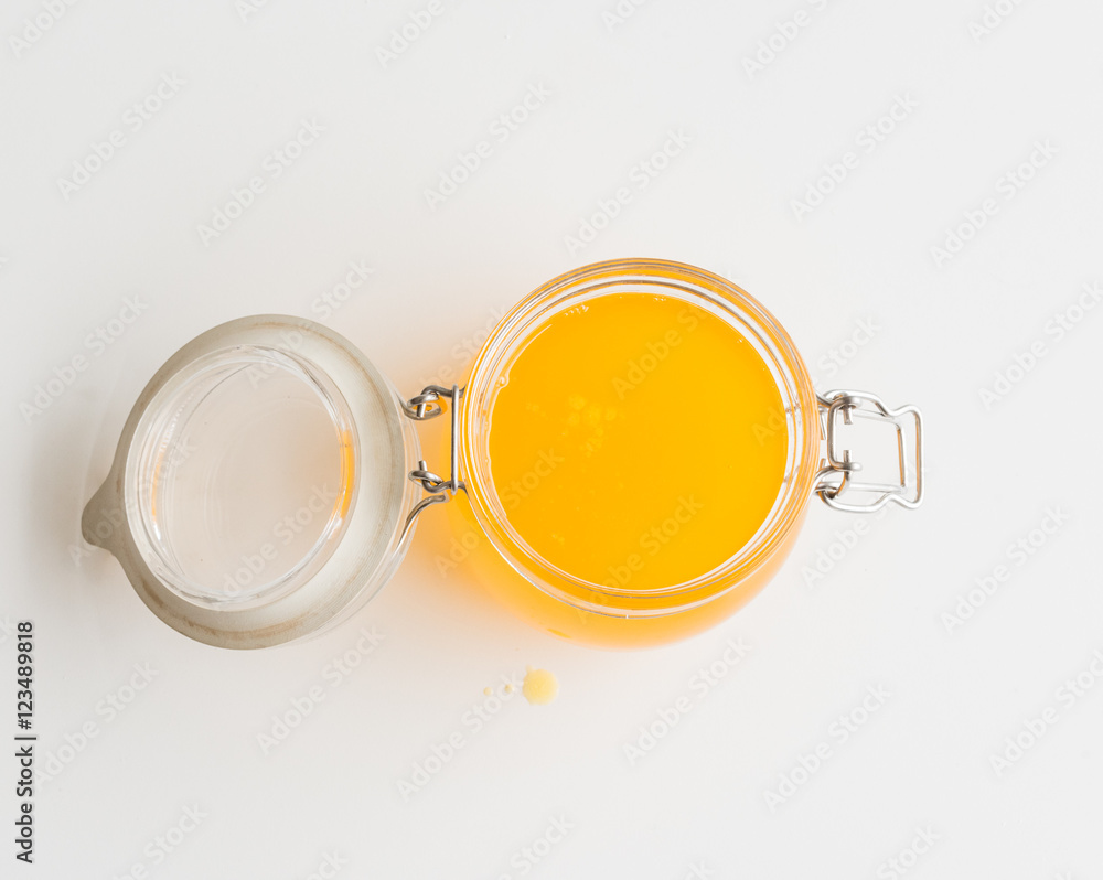 High angle view of just-poured homemade ghee (clarified butter) in glass jar on white table High angle view of just-poured homemade ghee (clarified butter) in glass jar on white table