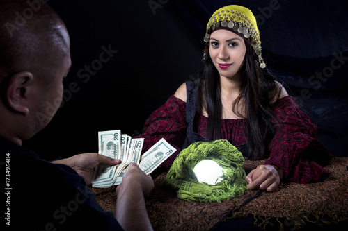 Female fortune teller psychic or con artist swindling money from a gullible male customer via fraud photo