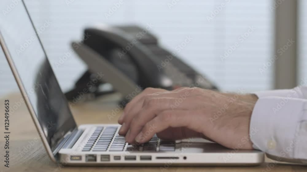 Male hands answering phone and typing in a modern office Male hands answering phone and typing in a modern office