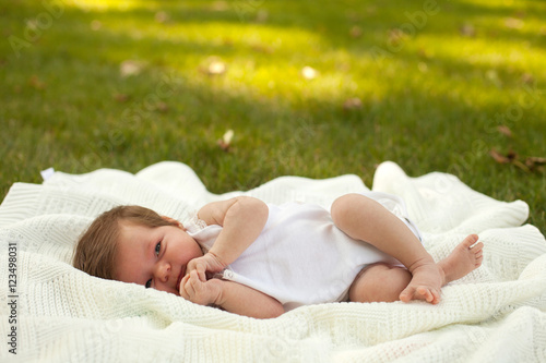 Baby lying on the blanket on the grass