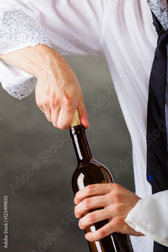 Waiter opens wine bottle.
