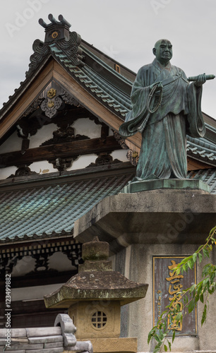 Kyoto, Japan - September 15, 2016: Statue of the monk Nichii who founded this Myoden-ji Buddhist Temple in Kyoto. Background is roof structure of the temple.