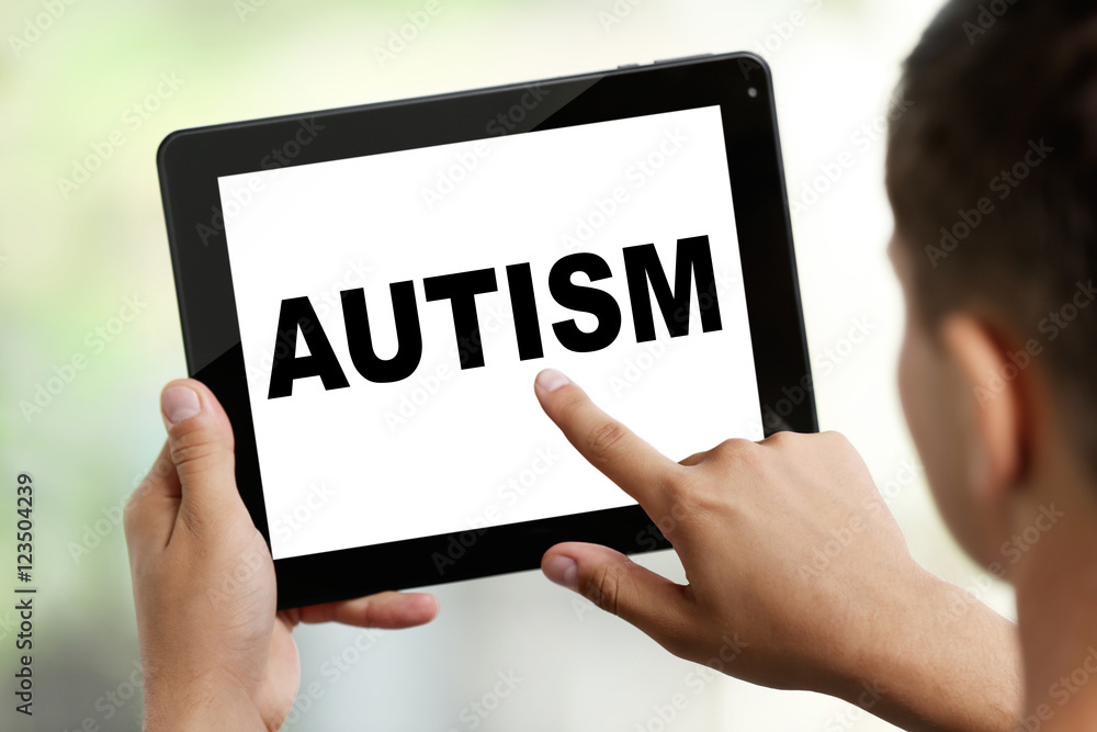 Children autism concept. Young man with tablet on blurred background Children autism concept. Young man with tablet on blurred background