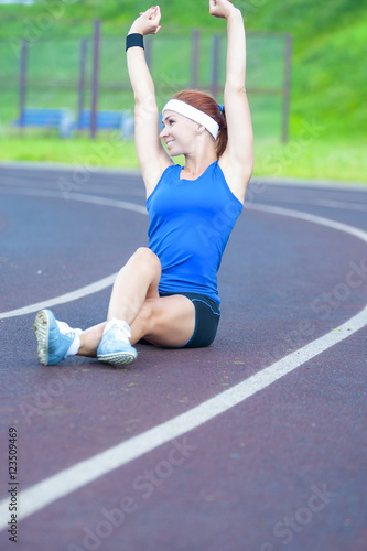 Red Haired Caucasian Sporstwoman Having Stretching Exercises On Stadium photo