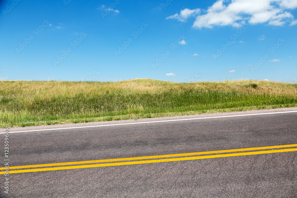 Fototapeta premium A road cutting through grasslands in southern South Dakota on a summer day. 