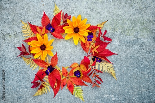 a wreath of autumn leaves and flowers on a neutral gray background, with copy space suitable for inscription on the autumn discounts.