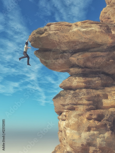 Young man hanging from a cliff