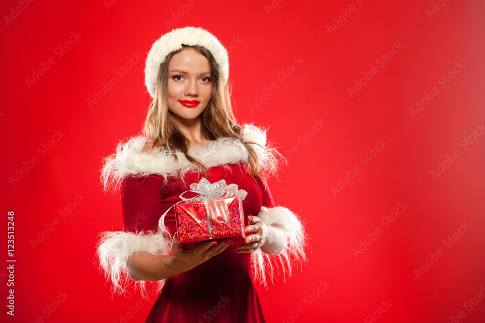 christmas, x-mas, winter, happiness concept - smiling woman in santa helper hat with gift box, over red background christmas, x-mas, winter, happiness concept - smiling woman in santa helper hat with gift box, over red background