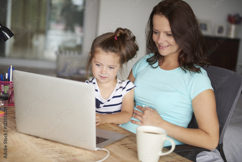 Daughter and mother use technology by computer Daughter and mother use technology by computer