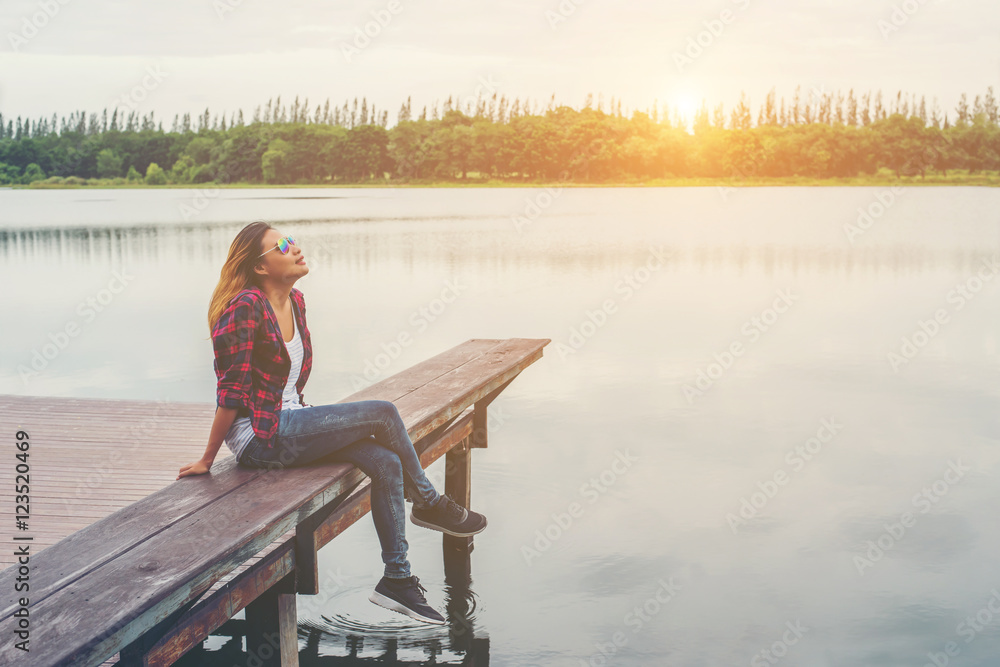 Young beautiful hipster woman sitting on the lake pier ,Relaxed Young beautiful hipster woman sitting on the lake pier ,Relaxed