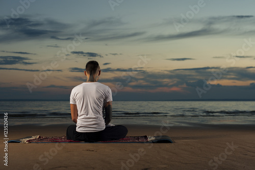 Yoga man sitting on the beach. Meditation pose