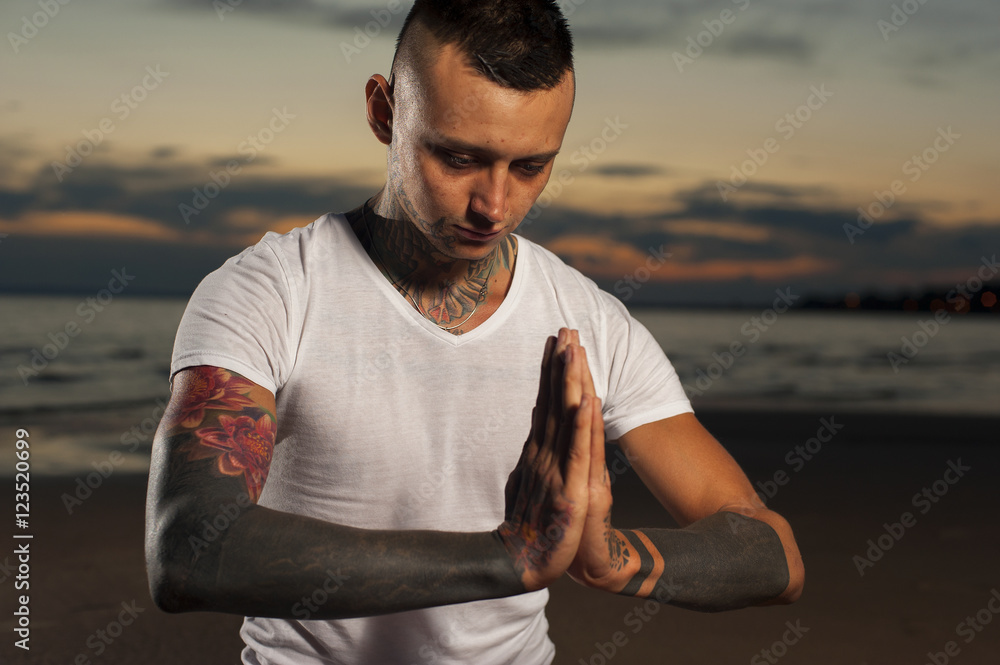 Man with tattoos doing yoga meditation Stock Photo | Adobe Stock