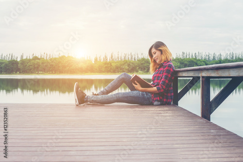 young beautiful hipster woman relaxing sitting on pier reading b