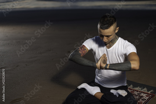 Young man in lotus position practicing yoga outdoors