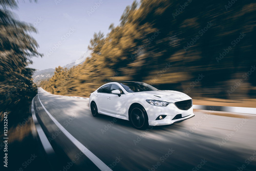 Fototapeta premium Biały samochód prędkości jazdy na drodze asfaltowej w ciągu dnia