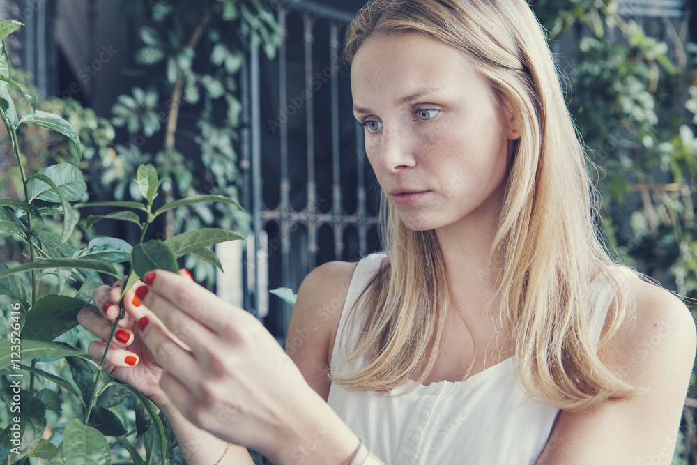 Young woman looking at plants on terrace