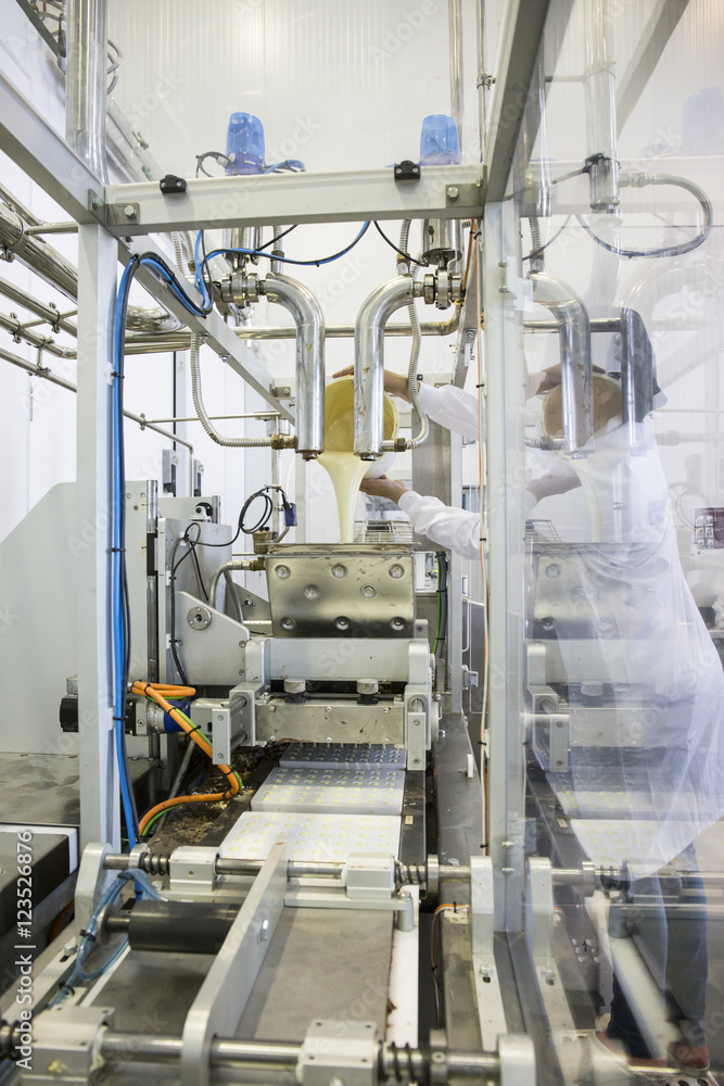 Woman pouring liquid white chocolate in a machine in a chocolate factory Woman pouring liquid white chocolate in a machine in a chocolate factory