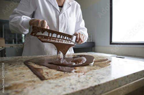 Woman tempering melted chocolate on a marble surface photo