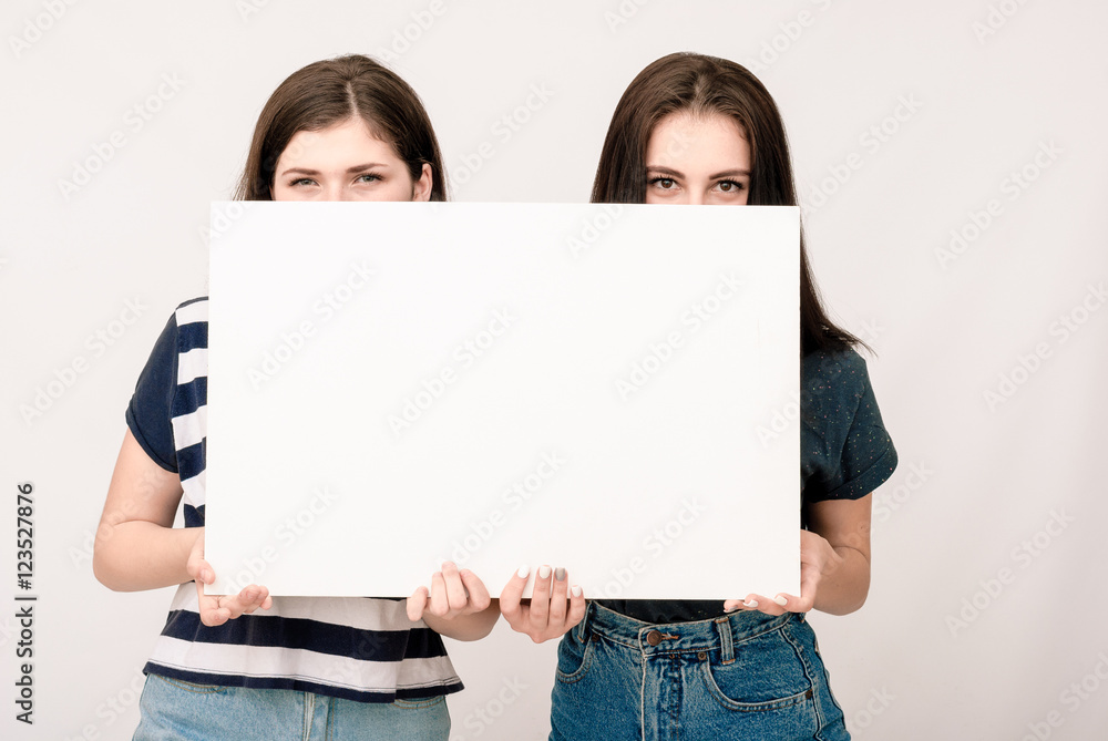 Two happy smiling young women carring big blank signboard