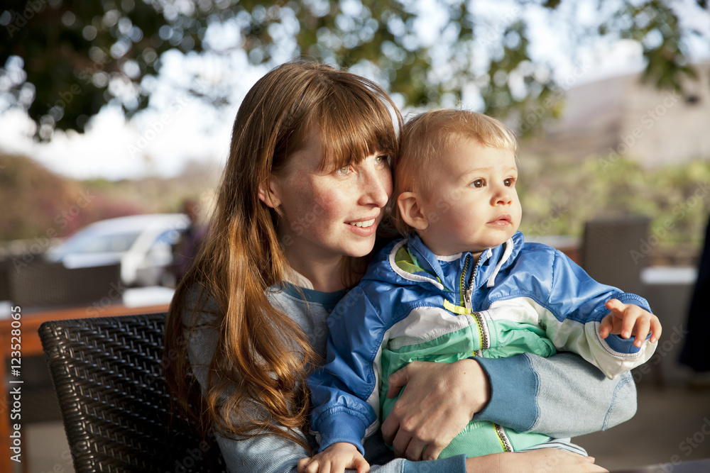 Mother and son sitting on chair looking around Mother and son sitting on chair looking around