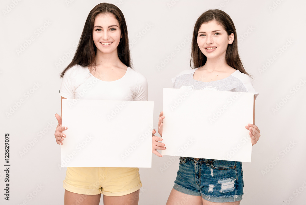 Two happy smiling young women carring big blank signboard Two happy smiling young women carring big blank signboard