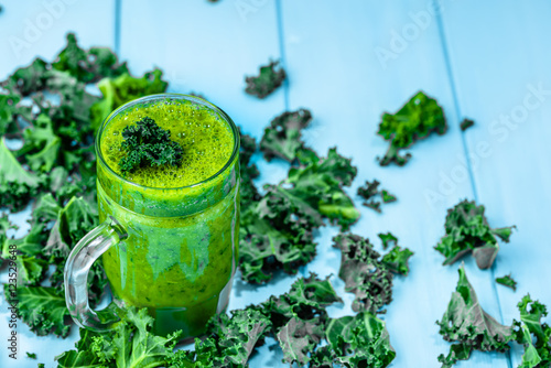 Glass of smoothie with green vegetables, leaves of kale in a jar