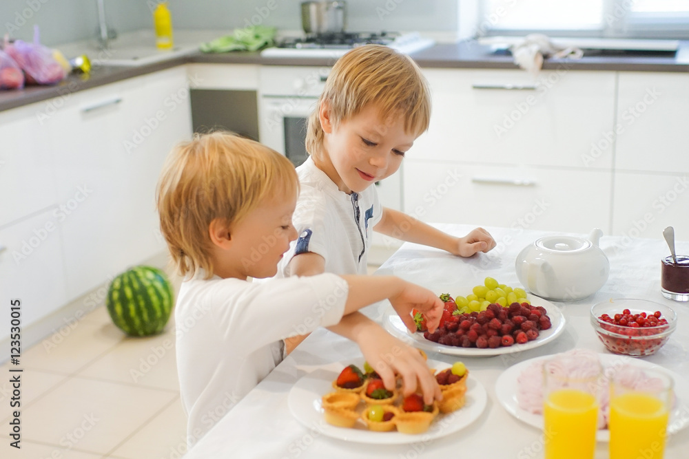 Two boys preparing breakfast in white kitchen