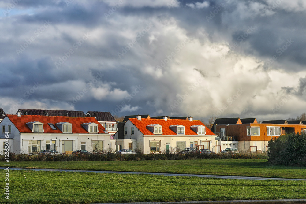 Fototapeta premium Sunshine on houses under a thunder sky