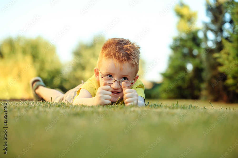 Happy baby boy with red hair in glasses on grass Happy baby boy with red hair in glasses on grass