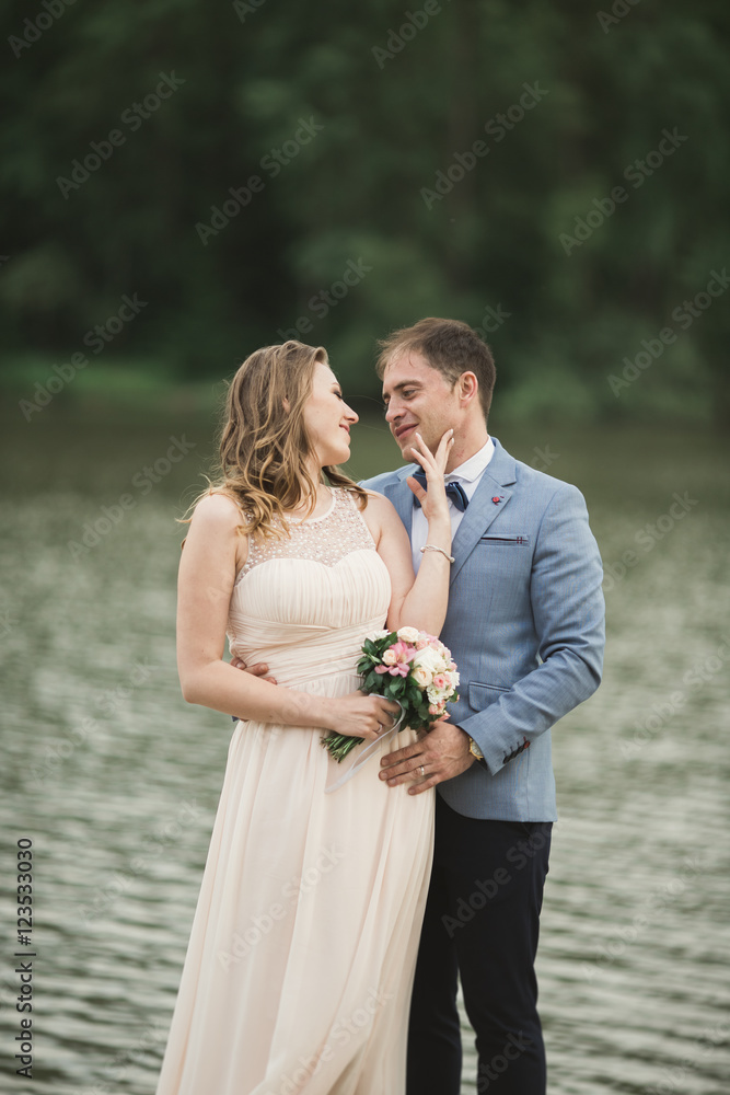 Elegant beautiful wedding couple posing near a lake at sunset Elegant beautiful wedding couple posing near a lake at sunset