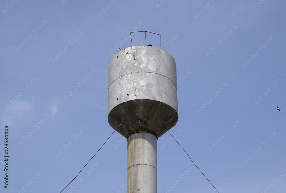 Silver Water Tower among green grass and trees Silver Water Tower among green grass and trees