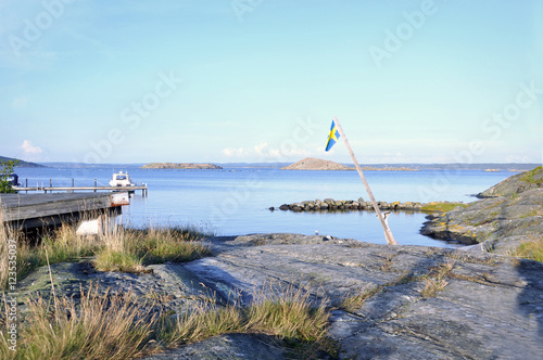 Sommardag på västkusten. En gammal svensk flagga svajar i luften ovanför klipporna.  photo