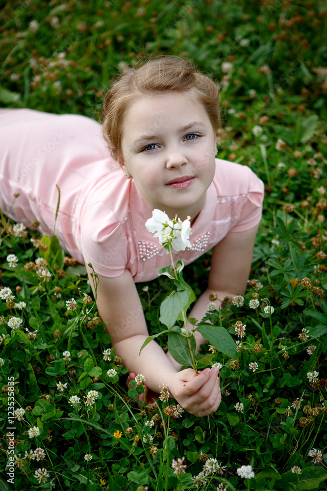 Portrait of a beautiful girl outdoors sitting on grass with flowers Portrait of a beautiful girl outdoors sitting on grass with flowers