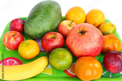 Fototapeta Naklejka Na Ścianę i Meble -  Assorted fruit on a green tray. Colorful sweet aromatic fruits for raw eating or squeezing or preparing smoothie. White background