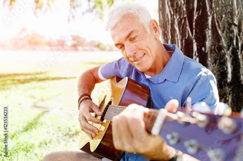 Senior man plying guitar outdoors