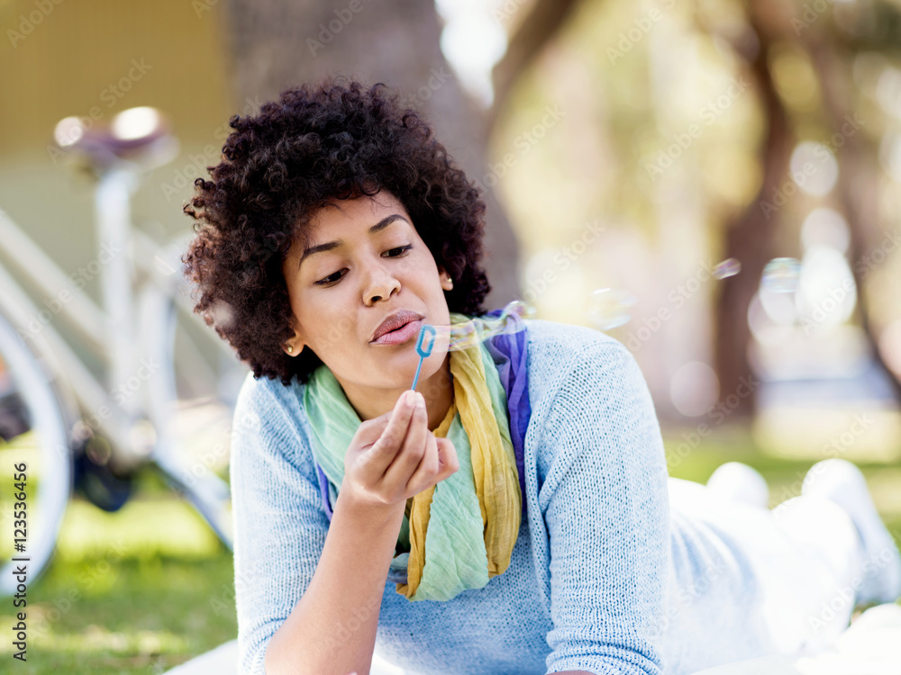 Fototapeta premium Beautiful woman blowing bubbles in park