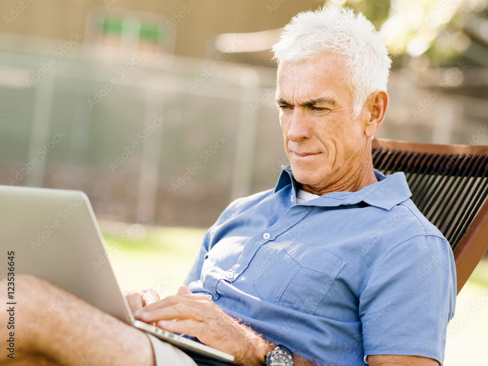 Senior man with notebook sitting in the park Senior man with notebook sitting in the park