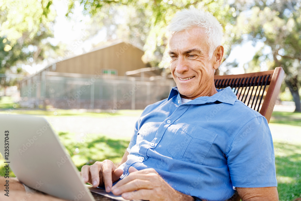 Senior man with notebook sitting in the park Senior man with notebook sitting in the park