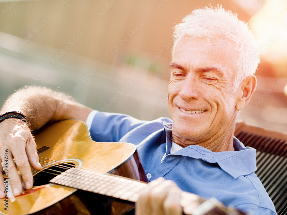 Senior man plying guitar outdoors Senior man plying guitar outdoors