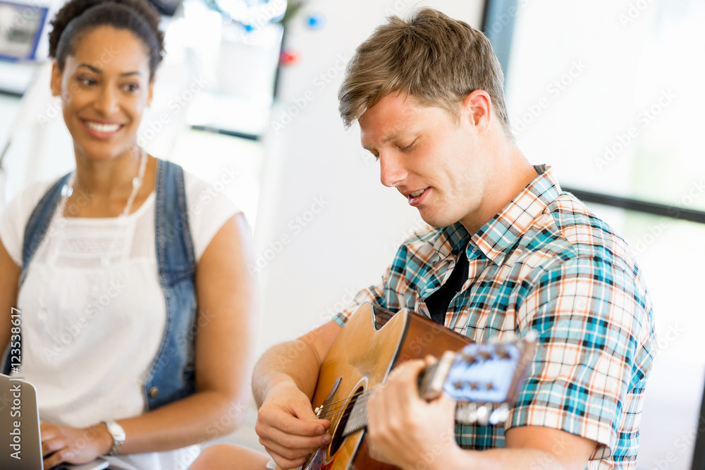 Students sitting on the floor with one playng guitar Students sitting on the floor with one playng guitar