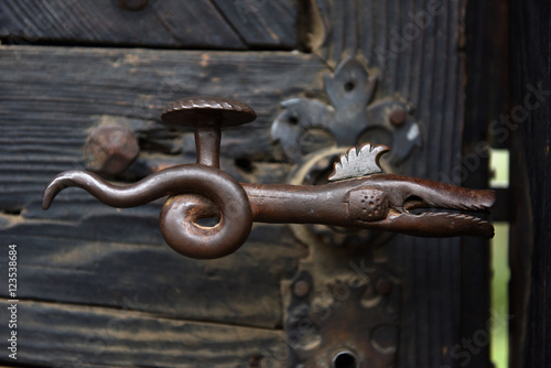 Ornamental vintage iron door handle on wooden door